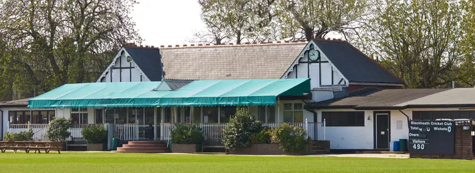 The Rectory Field clubhouse and its awning, seen across the cricket ground