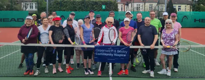 Members lined up along the net holding rackets in support of Greenwich & Bexley Community Hospice
