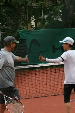 Two members reaching to shake hands across the net after a match