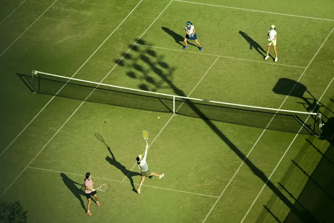 Four players competing in a doubles match on a grass court